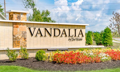 Welcoming "Vandalia" sign amid lush greenery and flowers, evoking warmth, positivity, and community pride.