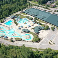 Aerial view of a vibrant water park with pools, slides, lounging areas, and greenery, evoking summer fun and relaxation.