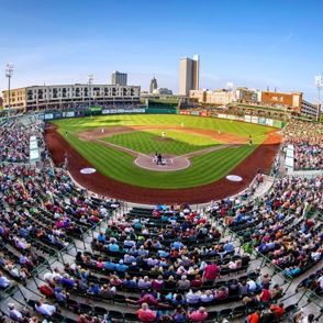 A lively baseball stadium filled with excited spectators under a clear blue sky, highlighting enjoyment and community spirit.