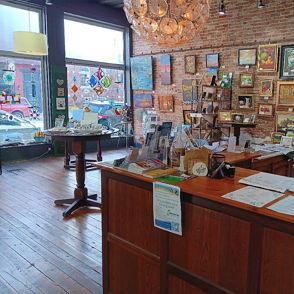 Cozy art gallery with framed artworks, warm wooden interiors, natural light, and an inviting atmosphere for creativity and community.