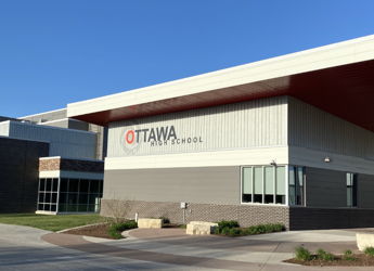 Modern Ottawa High School building with sleek design, large windows, and vibrant landscaping under a clear blue sky.
