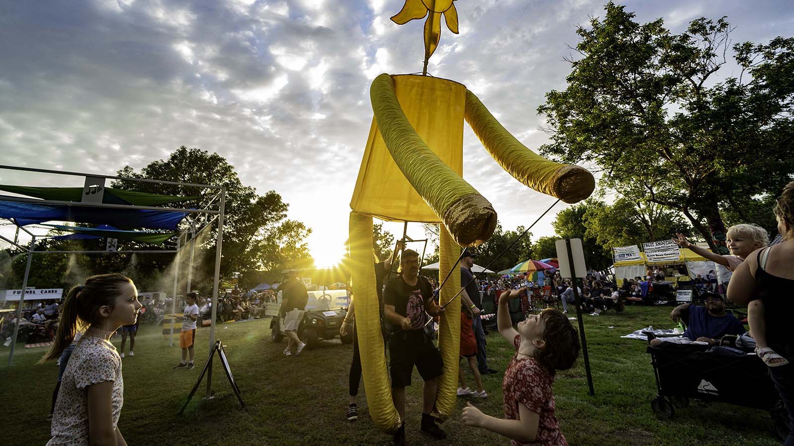Colorful puppet at a festival; children joyfully engage, capturing a sense of community, happiness, and wonder.