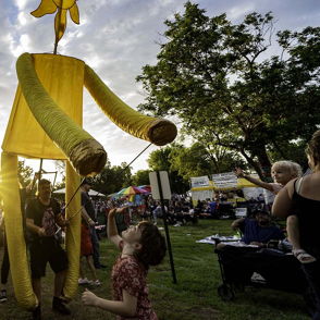 Colorful puppet at a festival; children joyfully engage, capturing a sense of community, happiness, and wonder.