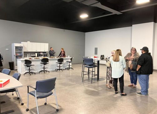 A modern, spacious interior with people socializing, suggesting a friendly networking atmosphere and community spirit.