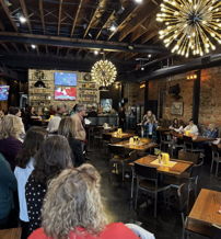 Lively restaurant interior with cozy lighting, engaging crowd, and modern decor evokes joy, warmth, and community spirit.