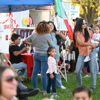 Lively outdoor gathering with diverse people, joyful interactions, colorful decor, and a festive, family-friendly atmosphere.