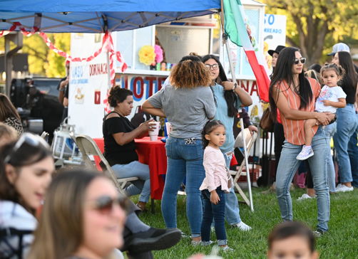 Lively outdoor gathering with diverse people, joyful interactions, colorful decor, and a festive, family-friendly atmosphere.