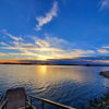 Serene lakeside scene at sunset with a colorful sky, reflecting water, and inviting stairs for contemplation and relaxation.