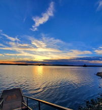 Serene lakeside scene at sunset with a colorful sky, reflecting water, and inviting stairs for contemplation and relaxation.