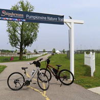 Scenic pathway to Pumpkinvine Nature Trail with bicycles parked, showcasing a peaceful, lush outdoor environment.