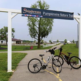 Scenic pathway to Pumpkinvine Nature Trail with bicycles parked, showcasing a peaceful, lush outdoor environment.