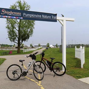 Scenic pathway to Pumpkinvine Nature Trail with bicycles parked, showcasing a peaceful, lush outdoor environment.