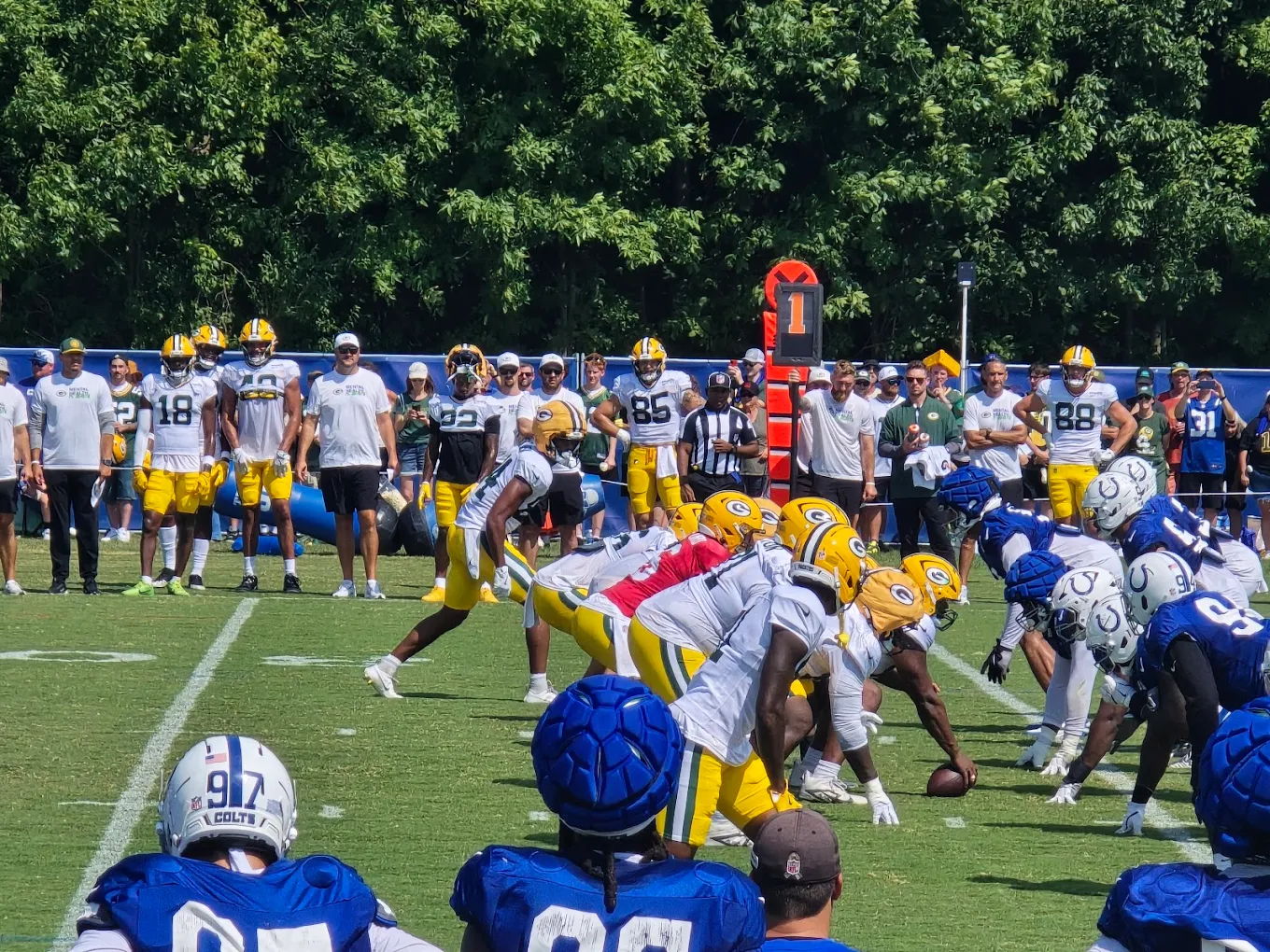 Football practice scene with players in yellow and blue uniforms, focused on their play under a sunny, vibrant atmosphere.