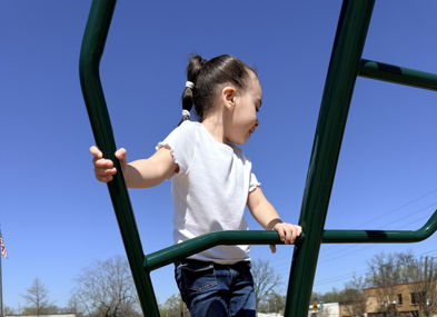 A child in a white shirt and jeans climbs a playground, embodying joy, curiosity, and the spirit of carefree play.
