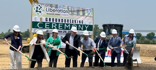 Group in white hard hats at a groundbreaking ceremony, shovels in hand, evokes optimism and teamwork for new beginnings.