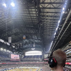 A young boy in headphones shares excitement in a lively indoor stadium during a vibrant motorsport event.