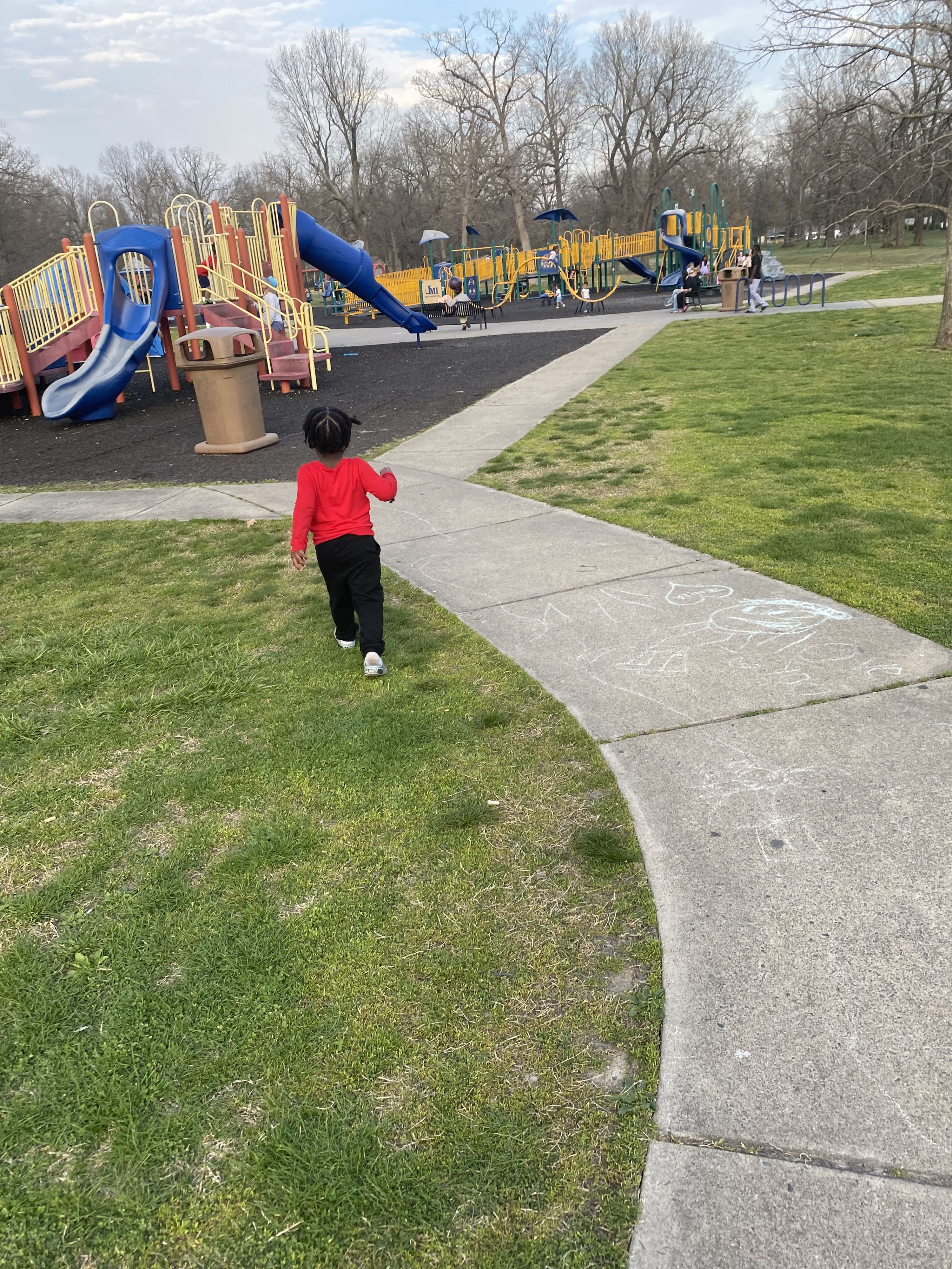 A child in a red jacket walks away in a lively park, evoking joy, innocence, and a sense of adventure.