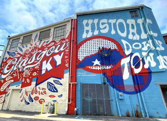 Vibrant mural on a building in Glasgow, KY, featuring bold colors, community pride, and a lively urban art style.