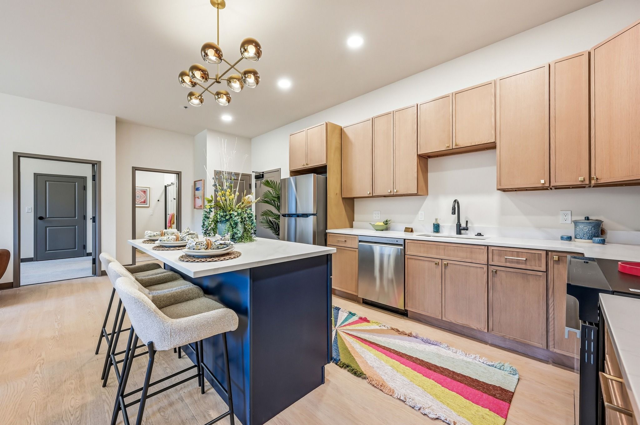 Modern kitchen with warm wood cabinetry, stainless steel appliances, a spacious island, and cozy lighting for inviting gatherings.
