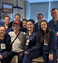 Healthcare professionals and a smiling patient pose together in a warm, supportive hospital setting, reflecting joy and camaraderie.