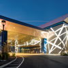 Modern building with sleek architecture, vibrant lights, and a serene dusk backdrop, evoking excitement and curiosity.