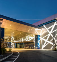 Modern building with sleek architecture, vibrant lights, and a serene dusk backdrop, evoking excitement and curiosity.