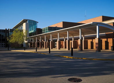 Modern school building with brick and glass architecture, featuring a bright, inviting entrance and a peaceful atmosphere.