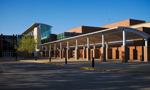 Modern school building with brick and glass architecture, featuring a bright, inviting entrance and a peaceful atmosphere.