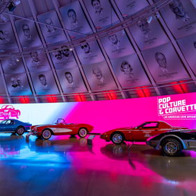 Vibrant exhibition of classic and modern Corvettes with colorful lighting, showcasing automotive history and pop culture.