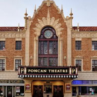 Exterior of Poncan Theatre, blending classical and Art Deco styles, featuring a marquee, clock, and vintage charm.
