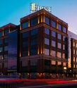 Modern building with glass and brick, illuminated at twilight, evokes calmness and vibrancy during a serene dusk.