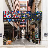 A vibrant alleyway with a colorful geometric arch invites exploration, blending urban life with artistic expression.