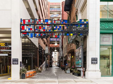 A vibrant alleyway with a colorful geometric arch invites exploration, blending urban life with artistic expression.