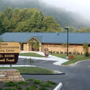 Gladie Cultural-Environmental Learning Center, rustic design, surrounded by greenery and misty mountains, evokes tranquility.