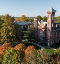 Brick building surrounded by vibrant autumn foliage and a clear blue sky, evoking nostalgia and tranquility.