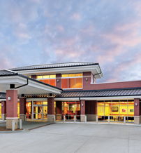 Modern building with large windows and polished exterior, set against a serene pastel sky, evoking warmth and hospitality.