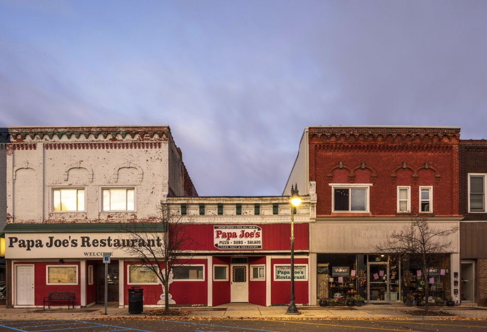 Quaint street scene featuring "Papa Joe's" restaurant, with charming brickwork, inviting signage, and a peaceful evening sky.