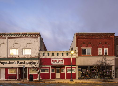 Quaint street scene featuring "Papa Joe's" restaurant, with charming brickwork, inviting signage, and a peaceful evening sky.