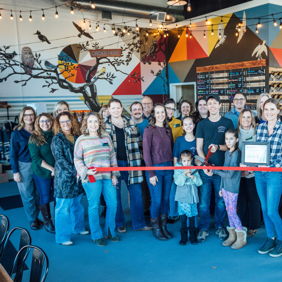 Group celebration at a grand opening, vibrant decor, smiling attendees, and a joyful, family-friendly atmosphere.