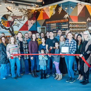 Group celebration at a grand opening, vibrant decor, smiling attendees, and a joyful, family-friendly atmosphere.
