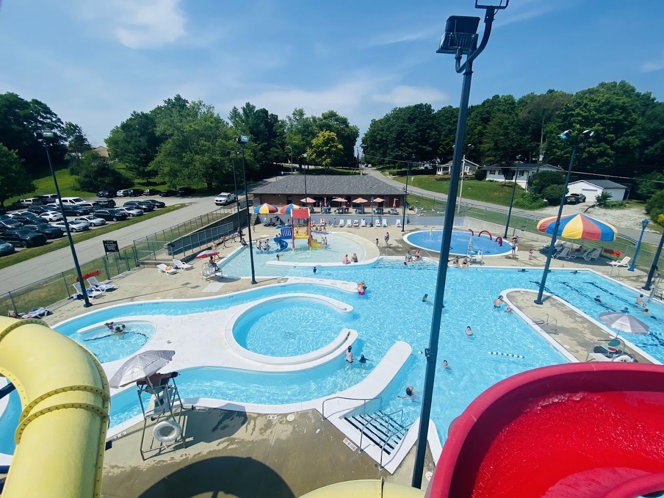 A vibrant water park scene with pools, slides, families, and colorful umbrellas, evoking joy and summer fun.