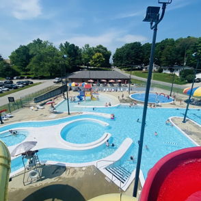 A vibrant water park scene with pools, slides, families, and colorful umbrellas, evoking joy and summer fun.