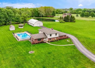 A peaceful rural scene with a house, pool, barn, and green lawn, evoking calm and connection to nature.