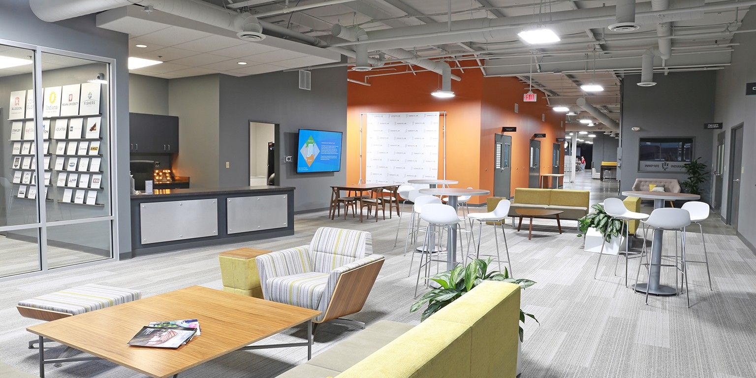 Modern office workspace with warm hues, varied seating, natural light, fostering creativity, collaboration, and comfort.