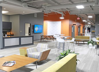 Modern office workspace with warm hues, varied seating, natural light, fostering creativity, collaboration, and comfort.