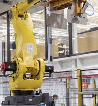 A yellow robotic arm in a bright industrial space symbolizes innovation, efficiency, and contemplation of automation's impact.