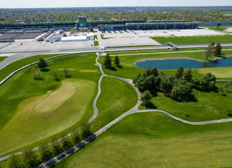 Aerial view of a lush golf course, serene pond, and stadium, blending sports excitement with nature's tranquility.