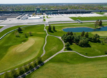 Aerial view of a lush golf course, serene pond, and stadium, blending sports excitement with nature's tranquility.
