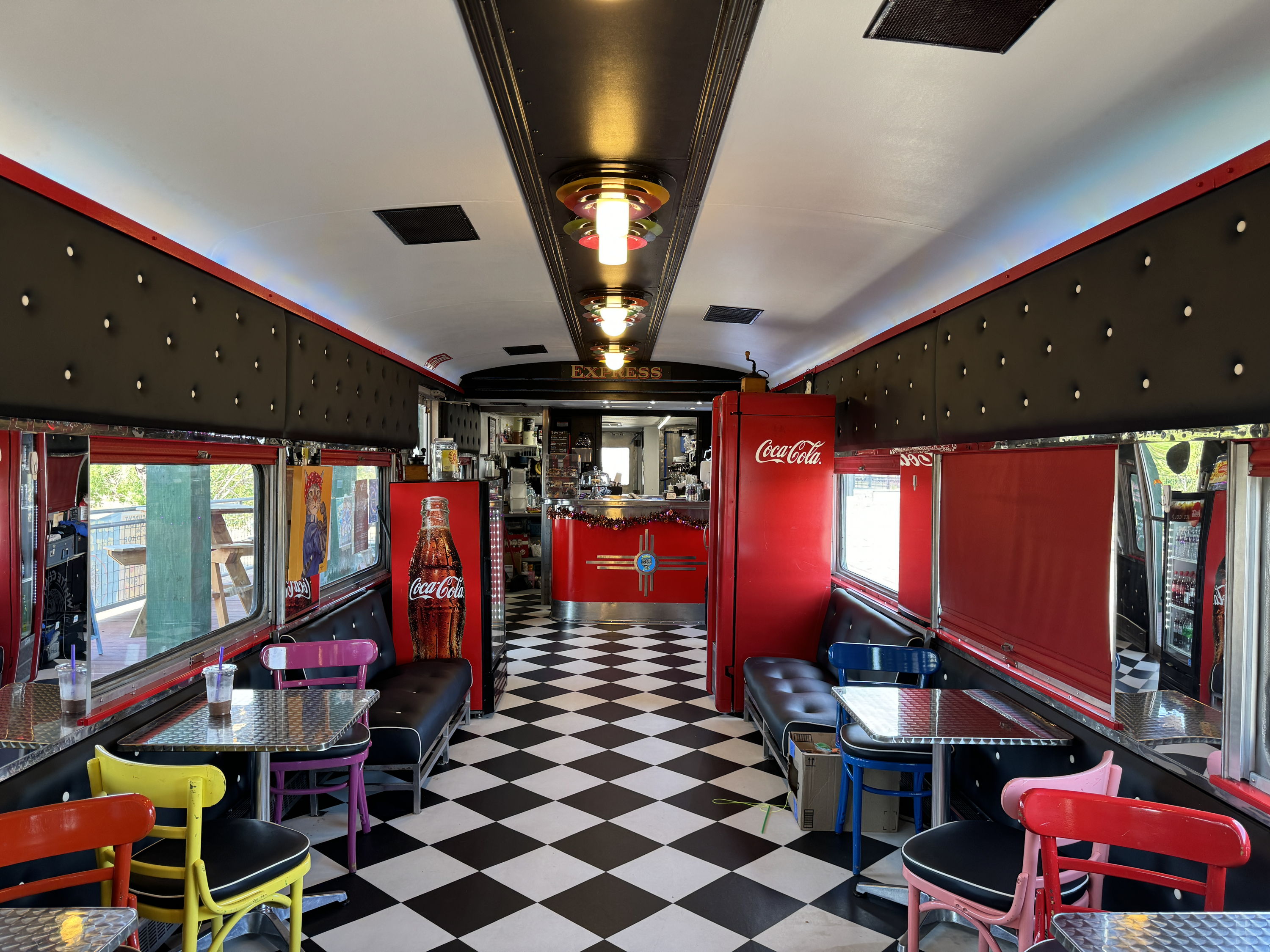 A vibrant retro diner with checkered floors, colorful chairs, and nostalgic decor, evoking warmth and cheerfulness.