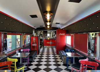 A vibrant retro diner with checkered floors, colorful chairs, and nostalgic decor, evoking warmth and cheerfulness.